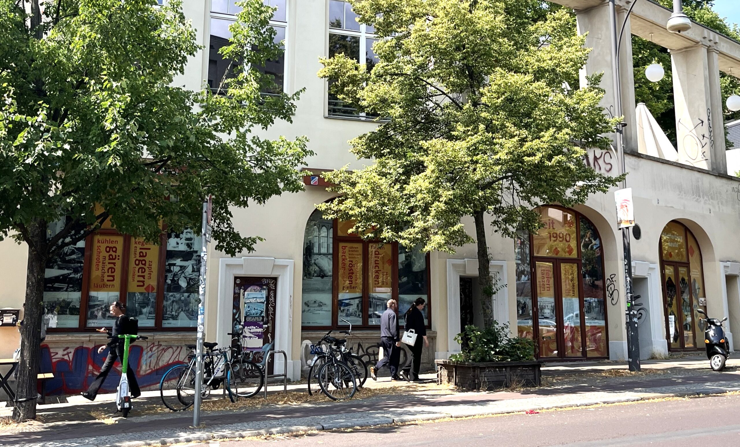 Beklebte Rundbogen-Fenster an einer Straße , davor Fahrräder und Bäume
